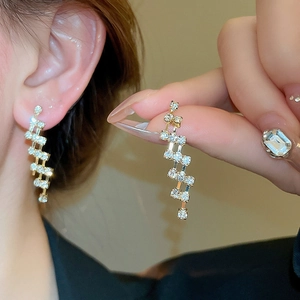 Detail of elegant gold-tone geometric tassel earrings with micro-set sparkling crystals