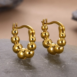 Macro view of 18k gold plated beaded earrings showing polished finish on a stone base
