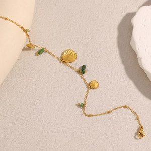 Détail d'une chaîne de cheville plaquée or 18K avec pendentif coquillage et perles