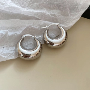 Close-up of chunky silver dome hoop earrings with glossy finish and secure clasp