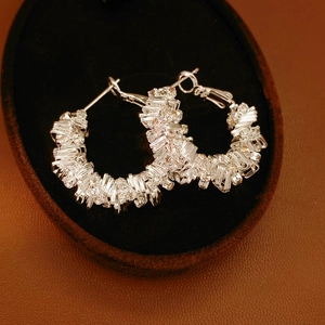 Detailed macro view of silver irregular geometric earrings with sparkling diamond texture
