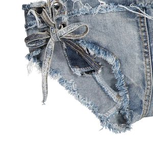 Dettaglio di pantaloncini in denim azzurro usurato con lacci laterali e bordi sfrangiati