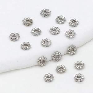 Macro shot of silver snowflake-shaped spacer beads for DIY jewelry making