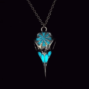 Macro shot of Viking raven skull necklace with luminous blue patterns on dark background