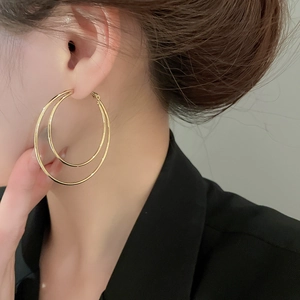 Close-up of double-layer gold hoop earrings on a model for a stylish and layered aesthetic