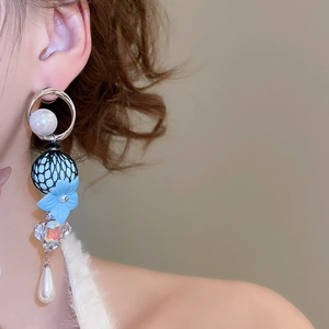 Detailed close-up of zircon pearl and resin flower drop earrings worn by a model