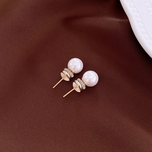 Macro detail of elegant double pearl stud earrings on vintage dark brown fabric background