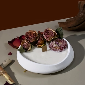 Detalle de vela aromática artesanal con rosas secas y mecha de madera en cuenco