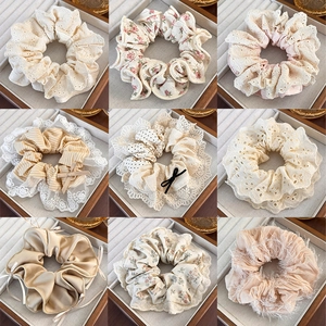 Collage of lace and floral fabric hair scrunchies in pastel tones on wooden trays