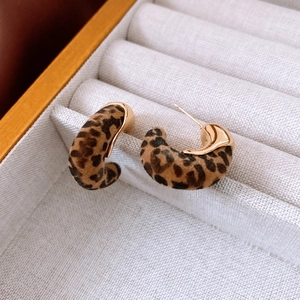 Gros plan de boucles d'oreilles en forme de C avec motif léopard et métal doré 18 carats