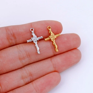 Handheld view of silver and gold stainless steel cross pendants with rose details