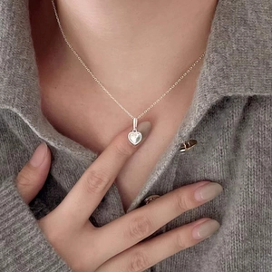Minimalist 925 sterling silver heart pendant necklace shown on neck with knitwear