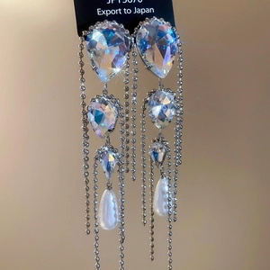 Macro shot of silver tassel earrings with AB crystals and teardrop pearls in elegant style