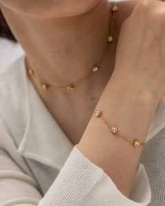 Detailed view of a gold bracelet with three inset round zircons worn on wrist