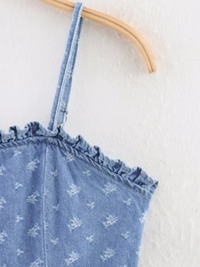 Dettaglio dell'abito in denim blu con stampa a stelle bianche e bordi a balze
