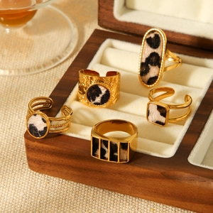 Set of 5 geometric leopard print stainless steel rings in gold displayed in jewelry box