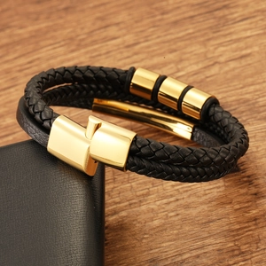 Macro shot of men's black braided leather bracelet with polished gold magnetic clasp detail