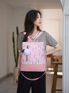 Detailed side view of pink floral Oxford fabric backpack with white plush charm pendant