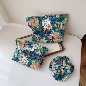 Close-up of three-piece blue floral fabric storage set with zipper pouches and scrunchie