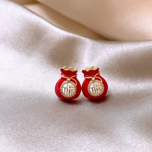 Détail macro de boucles d'oreilles sac de chance rouge avec pompons dorés