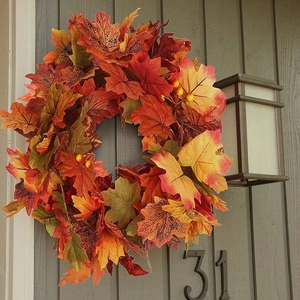 Autumn maple leaf garland with orange and red foliage and yellow berries on wood background