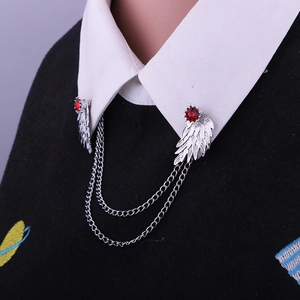 Detail showing silver wing collar pins with red gemstones and chains on shirt