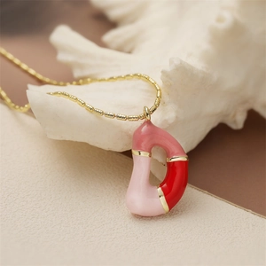 Détail du collier chaîne dorée avec pendentif lettre D en émail rose et rouge