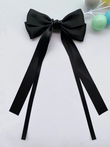 Dettaglio di un elegante fiocco in raso nero con lunghi nastri fluenti per capelli