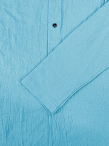 Detail of light blue cotton linen shirt showing texture and brown buttons on the placket