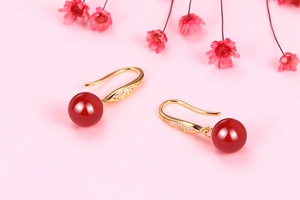 Detail of gold ear hooks with sparkling cubic zirconia and translucent red chalcedony beads