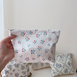 Detail view of cotton makeup bag featuring retro red cherry prints and zip closure