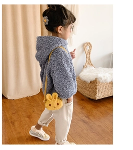 Detail view of a cute yellow plush rabbit crossbody bag styled with a blue teddy fleece coat