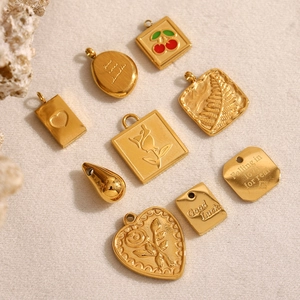 Macro shot of gold-plated stainless steel charms with heart, cherry, and rose designs