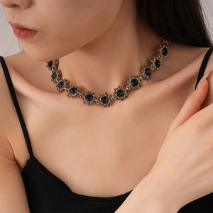 Detailed close-up of a vintage floral necklace with dark blue crystals on a model