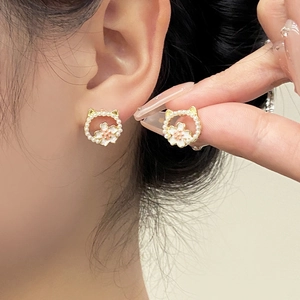 Detail of cat-shaped earrings featuring white pearls and a delicate center flower motif
