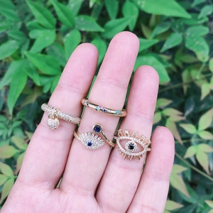 Golden Evil Eye ring set with colorful crystals and heart charm worn by a hand