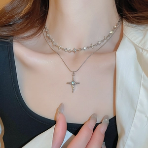 Detail of double-layer silver necklace with star pendants and cross blue gemstone