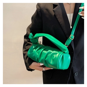 Detailed view of a green pleated cloud bag with a knotted handle on a model's shoulder