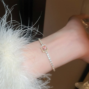 Detail of elegant gold bracelet featuring pink rectangular zircon stone and pavé setting