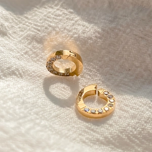 Macro detail of gold titanium steel jewelry connector buckle with clear stone inlay.
