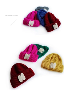 Close-up of thick ribbed knit texture and white N embroidery on colorful beanies