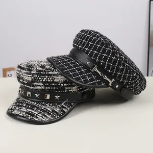 Flat lay of leopard and tweed military caps with studded leather brim and metal buckles