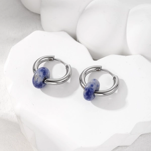 Detail view of silver hoop earrings with natural blue marble stones on white stone base
