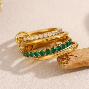 Detailed view of layered 18K gold plated rings with green and white zircon on wood