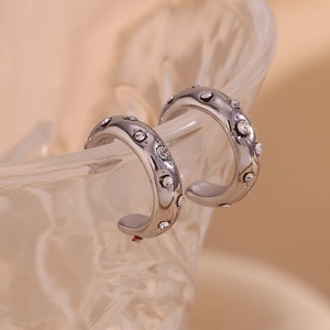 Macro shot of silver C-shaped clip earrings with sparkling rhinestones on glass