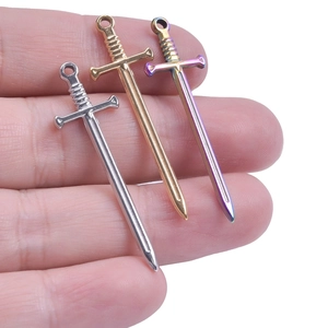 Detailed macro view of three-color sword pendants in silver, gold, and rainbow finishes