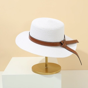 Detail of white woven straw hat featuring a brown faux leather belt with a side bow