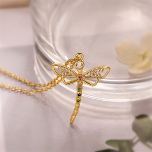 Macro detail of gold dragonfly pendant necklace featuring vibrant multi-color zircon stones
