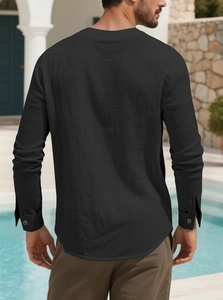 Detail of black cotton linen shirt with buttoned cuffs and curved hem by a resort pool