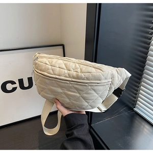 Detail view of beige quilted nylon crossbody bag with zipper and adjustable strap